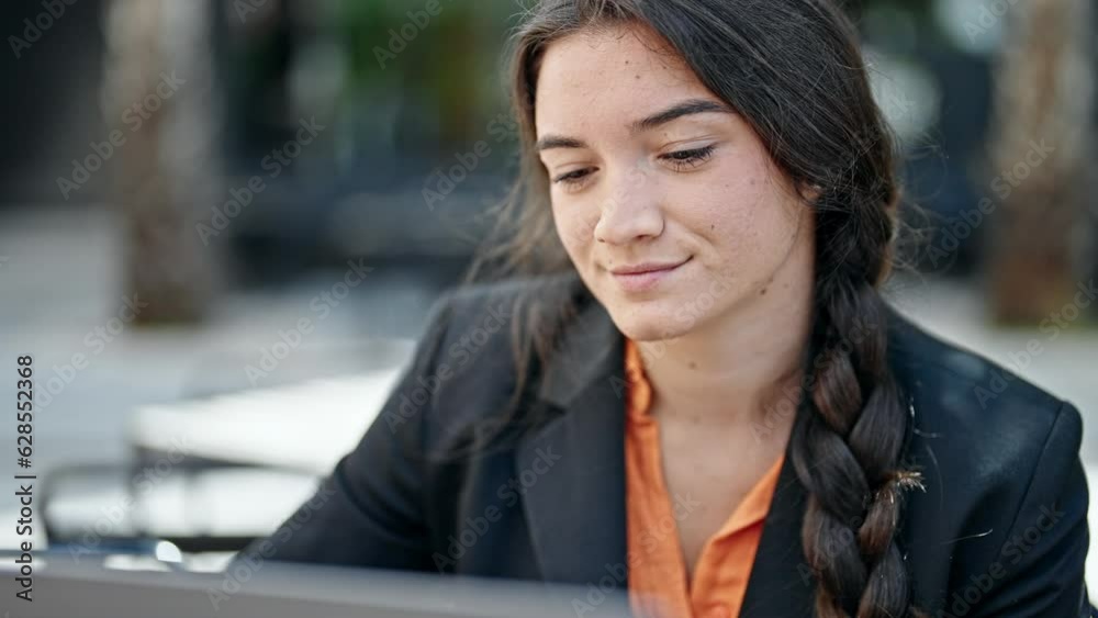 Young beautiful hispanic woman business worker using laptop smiling at coffee shop terrace