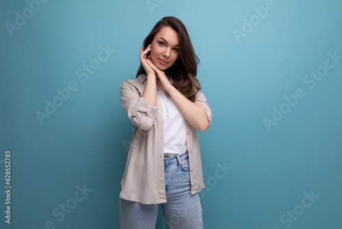 well-groomed brunette young woman in a stylish image posing on a blue background with copy space