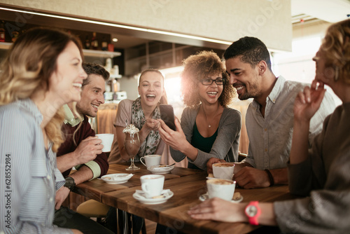 Tableau sur toile Diverse group of young people talking and having a coffee at a cafe