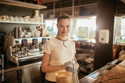 Portrait of a young female barista looking at the camera while working behind the counter at a cafe