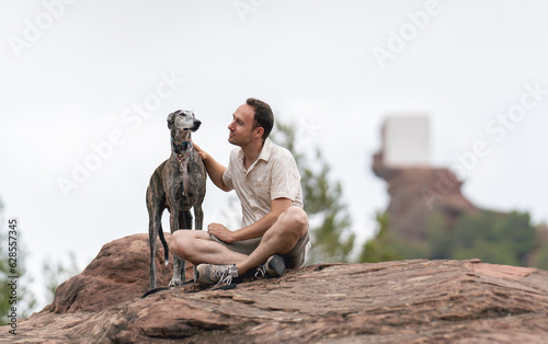 man sitting on a rock with his greyhound
