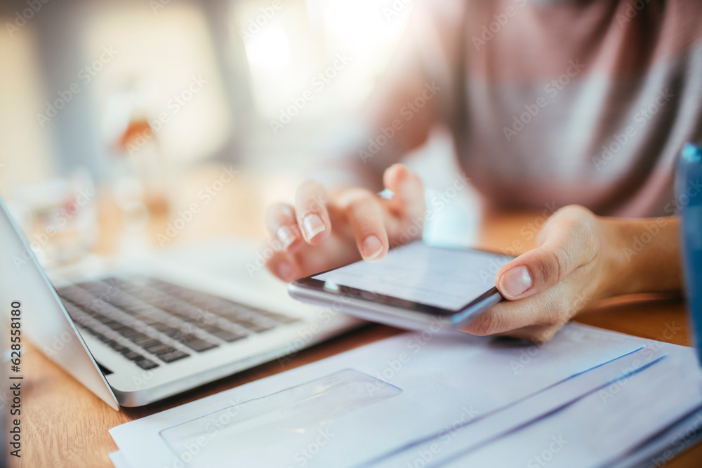 Young woman using a smart phone and laptop at home while working and studying Young woman using a smart phone and laptop at home while working and studying
