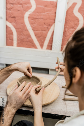 Romantic couple of artisans shaping clay earthenware on wooden board in ceramic studio photo