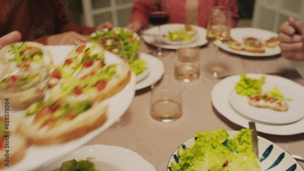 Medium close up of man giving plate with snacks to his friend when having festive evening at home Medium close up of man giving plate with snacks to his friend when having festive evening at home