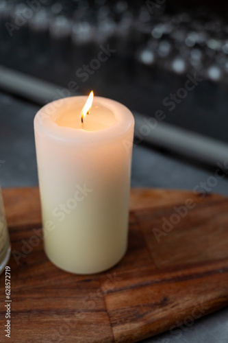 isolated lit candle with glassware in the background