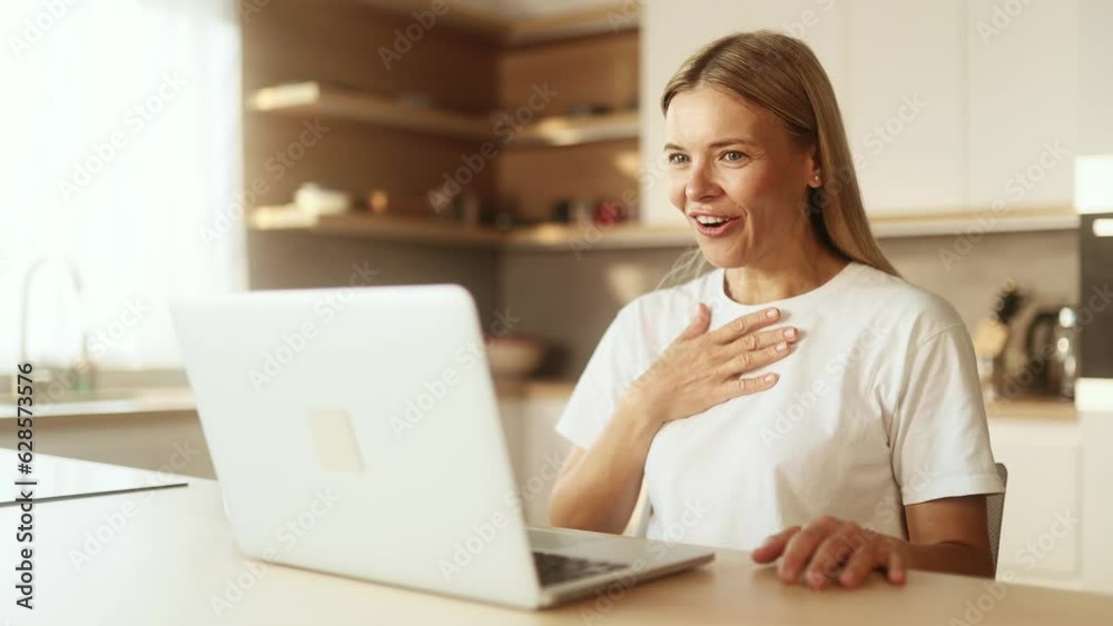 Portrait of beautiful blond woman having video call conference meeting by laptop computer at light home Smiling mature female talking on working or personal conversation indoors Portrait of beautiful blond woman having video call conference meeting by laptop computer at light home Smiling mature female talking on working or personal conversation indoors
