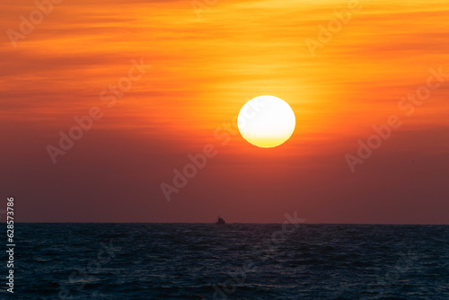 Sunset over the sea with a silhouette of a ship in the distance