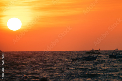 Silhouettes of fishing boats with sunset on the sea. The sun goes down on the sea.