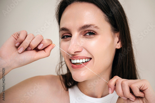 Portrait of smiling woman brushing teeth  using dental thread