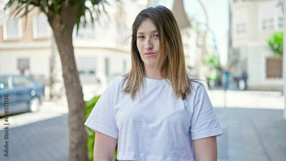 Young blonde woman looking to the side with serious expression saying no with finger at street