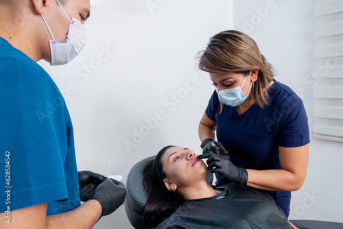 Cosmetologist applying a hyaluronic acid lip treatment to a young woman