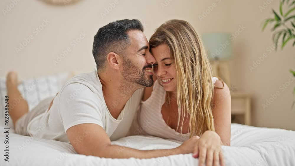 Man and woman couple lying on bed hugging each other kissing at bedroom Man and woman couple lying on bed hugging each other kissing at bedroom