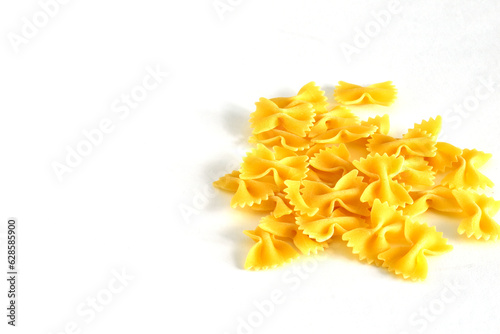Pile of dry farfalle yellow pasta over isolated white background