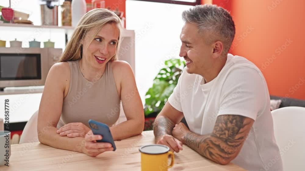 Man and woman couple using smartphone sitting on table at dinning room Man and woman couple using smartphone sitting on table at dinning room