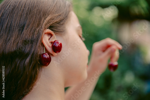 Cherries on the ears of a girl, close-up