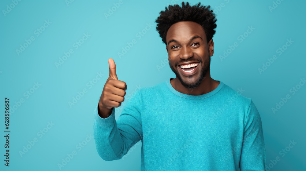 Young man standing over isolated blue background doing happy thumbs up gesture with hand. Young man standing over isolated blue background doing happy thumbs up gesture with hand.