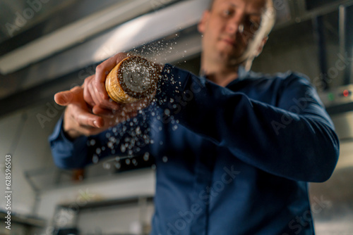 close-up of a chef holding a pepper and salt grinder in his hands grains of spices fall in the air