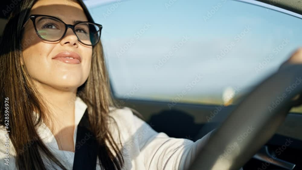 Young beautiful hispanic woman driving a car smiling wearing glasses on the road Young beautiful hispanic woman driving a car smiling wearing glasses on the road