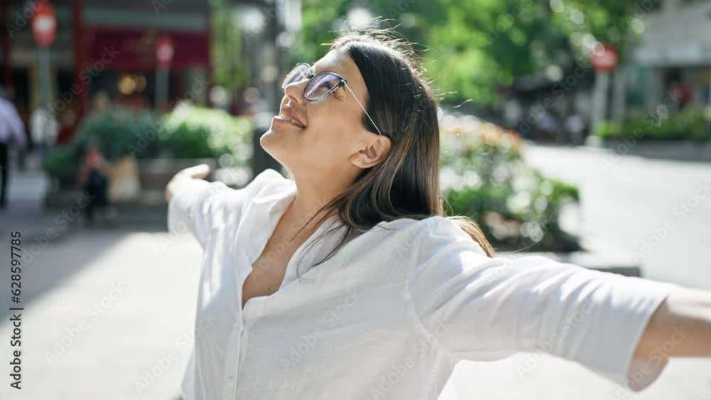 Young beautiful hispanic woman with open arms in the streets of Madrid
