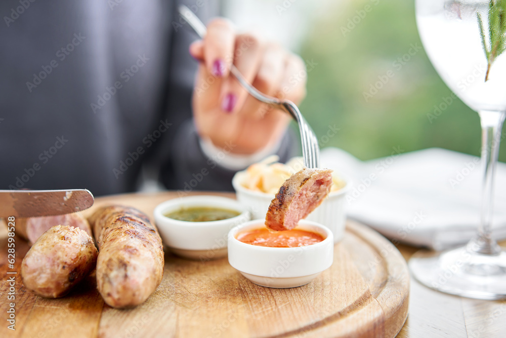 A piece of sausage is dipped in sauce. Lunch in a restaurant, a woman