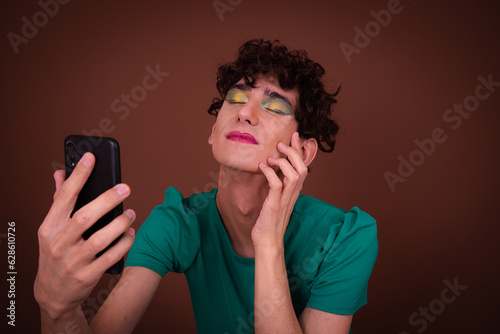 Drag queen poses in the studio and takes a selfie.