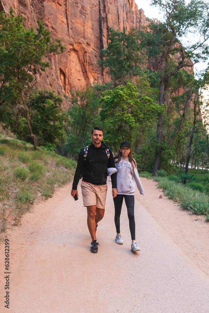 Father and his daughter hiking in the mountains. Family walking on pathway in Zion National Park, Utah, USA
