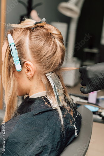 The process of hair coloring in a beauty salon. Blonde dyeing her hair