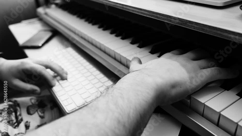 Creative music production: expert musician hands creating with mouse, keyboard, and playing electric keyboard piano (in black and white) photo