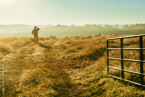 A farmer stands in a field full of ungrazed winter crabgrass near an open fence at end of summer in North Carolina photo