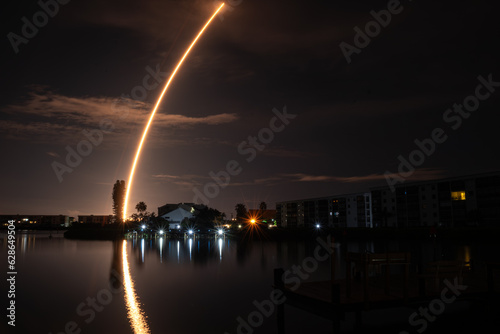 Reflections of Nighttime Rocket Launch over The Water  