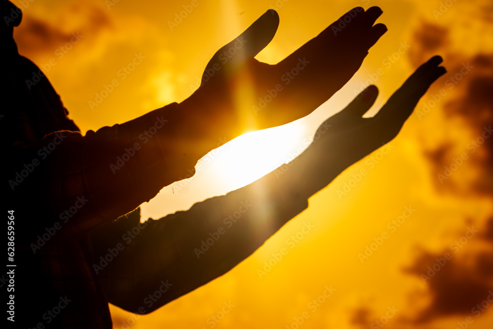 A powerful image capturing the silhouette of a man, his figure bathed in the golden glow of the setting solstice sun, engaged in a deep connection with the divine.