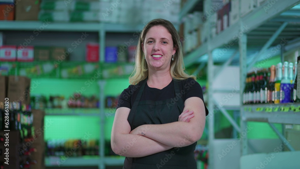 Joyful Woman Employee with Arms Crossed in Supermarket Aisle, Happy Expression Beside Store Inventory Joyful Woman Employee with Arms Crossed in Supermarket Aisle, Happy Expression Beside Store Inventory