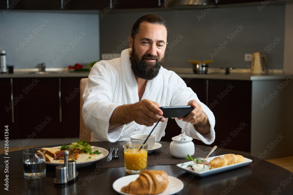 Hotel guest in a bathrobe sits at table with telephone Hotel guest in a bathrobe sits at table with telephone