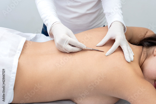 young woman on a table in a beauty center performing a beauty treatment for the skin of the back with the dermaplaning technique