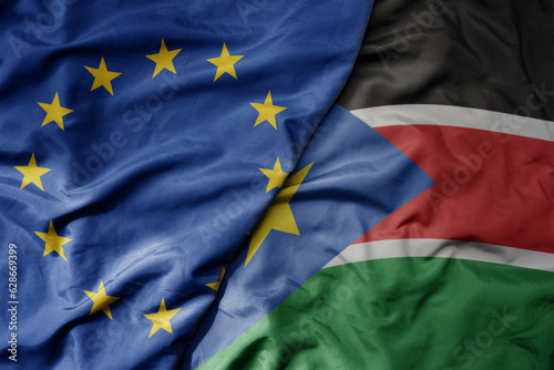 big waving realistic national colorful flag of european union and national flag of south sudan .