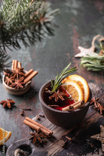 Mulled wine in ceramic mug with spices. Christmas hot drink on green wooden table with xmas tree branches