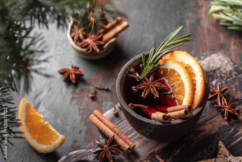Mulled wine in ceramic mug with spices. Christmas hot drink on wooden table with xmas tree branches