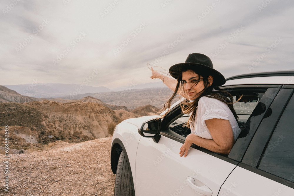 Naklejka premium Female traveler going out of the car window to appreciate the landscape