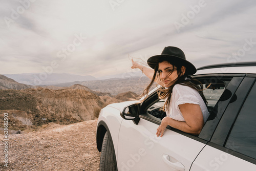 Female traveler going out of the car window to appreciate the landscape © Raul