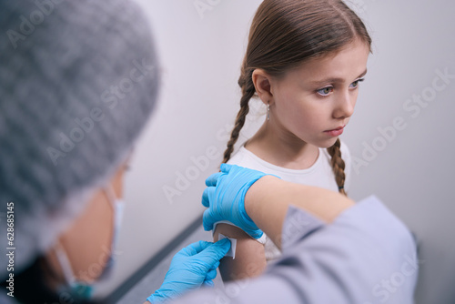 Nurse glues a patch on the hand of young patient