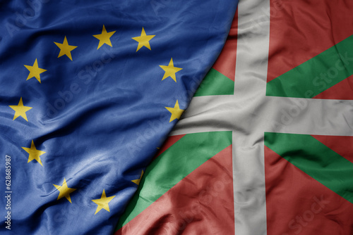 big waving realistic national colorful flag of european union and national flag of basque country .