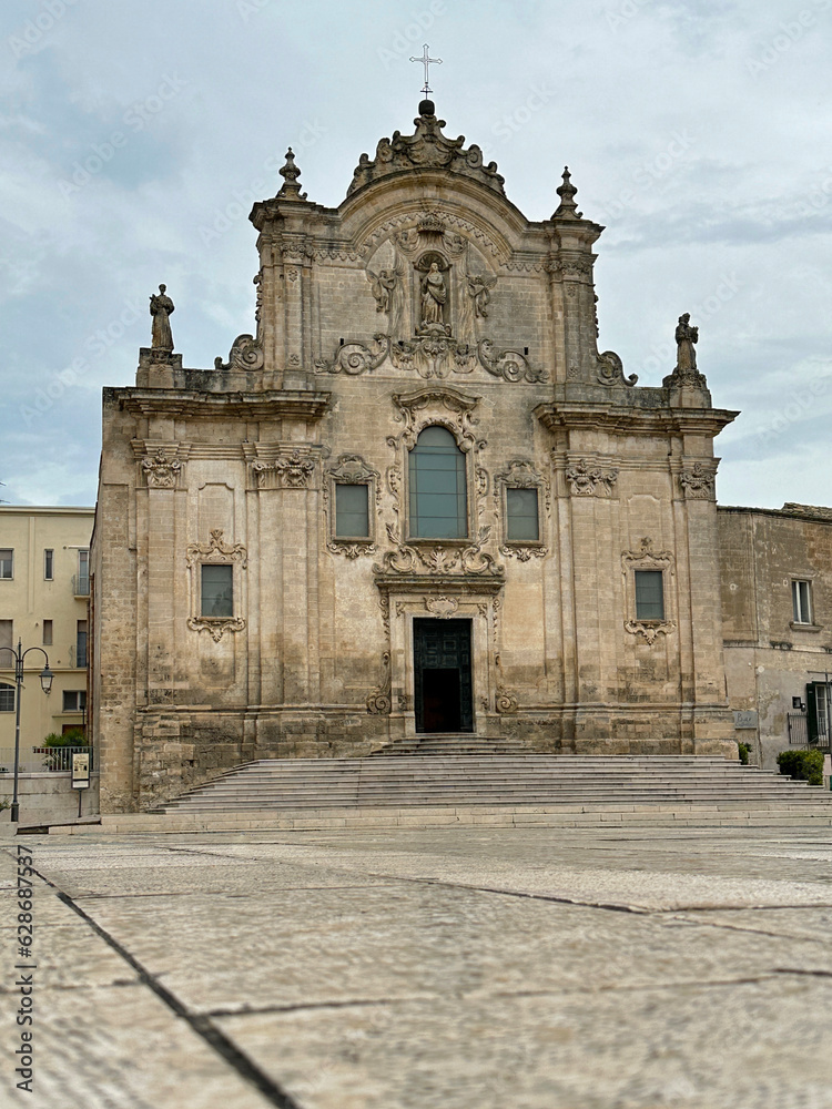 Chiesa di San Francesco d'Assisi (or Saint Francis of Assisi Catholic Church) of Matera, Italy is shown during the day in a vertical view.