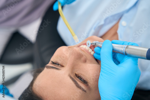 Canvas Print Close-up dentist smoothing and polishing uneven edges of female patient tooth
