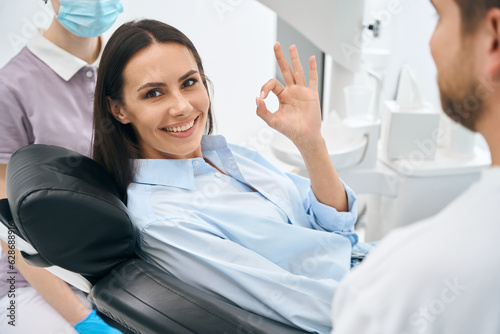 Fototapeta Positive woman client enjoying good service in private dental clinic, routine ch