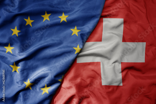 big waving realistic national colorful flag of european union and national flag of switzerland .