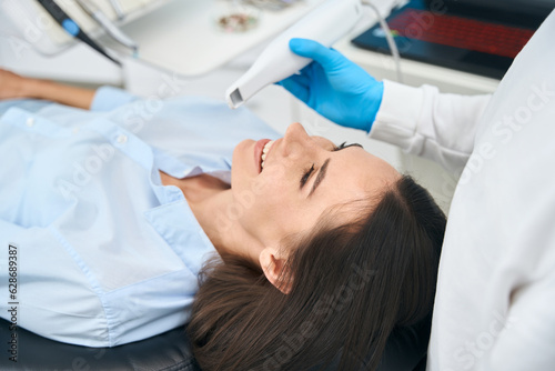 Dentist checking female client mouth health with dental intraoral camera