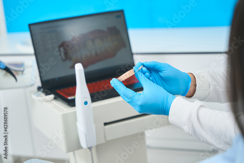 Dental technician making and cleaning prosthesis looking at tooth image photo