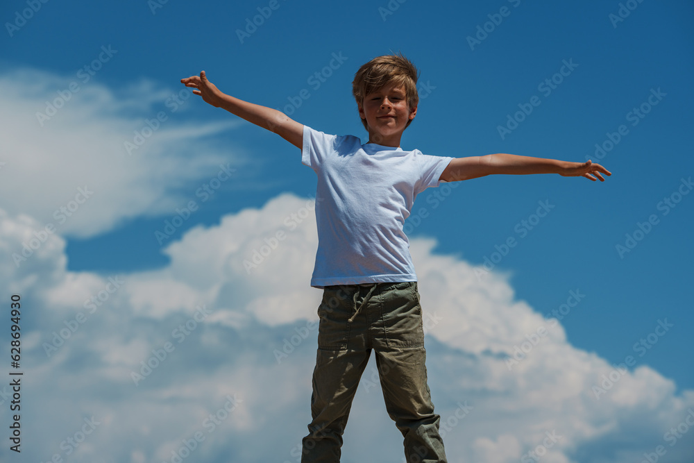 Happy boy standing on sky background enjoying freedom Happy boy standing on sky background enjoying freedom