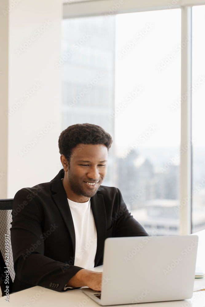 Smiling african american employee, using laptop, computer, freelancer working in modern office Smiling african american employee, using laptop, computer, freelancer working in modern office