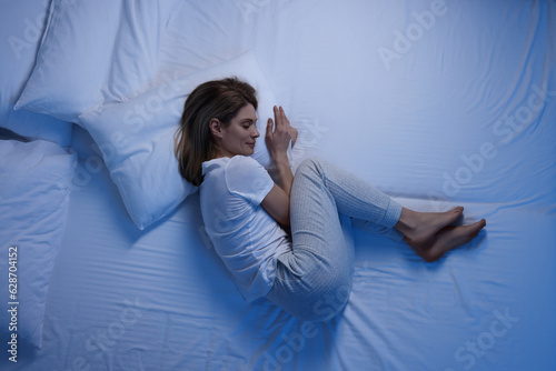 Canvastavla Woman sleeping in bed at night, top view
